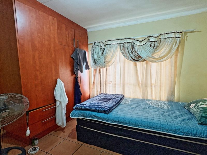 A bedroom featuring built-in wooden cupboards and tiled flooring, providing functional storage and a neutral base for interior updates.