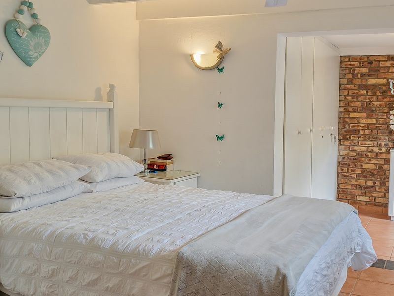 A bedroom featuring built-in cupboards, an exposed brick feature wall, tiled flooring, and an integrated air conditioning unit.