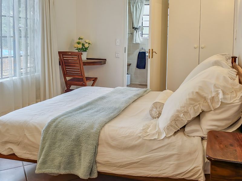 A well-maintained bedroom featuring tiled flooring, a built-in wardrobe, and direct access to an en-suite bathroom.