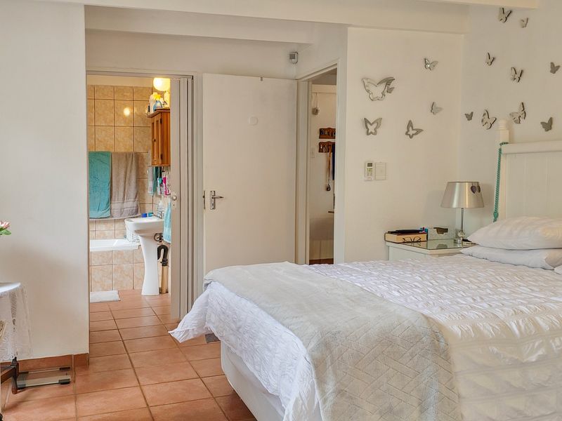 A bedroom featuring tiled flooring and direct access to an en-suite bathroom with a bathtub.