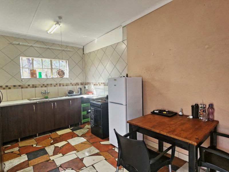 A functional kitchen featuring dark cabinetry, a stainless steel sink, tiled backsplash, and distinctive multi-colored tiled flooring.