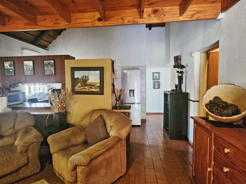 Open plan living area featuring exposed timber ceiling beams, tiled flooring, and a functional kitchen layout with a breakfast bar.