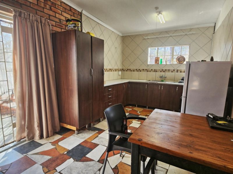 Kitchen featuring built-in cabinetry, tiled splashbacks, and an exposed brick feature wall, with direct access to the outdoor area via a sliding glass door.