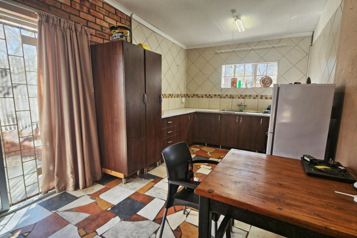 Kitchen featuring built-in cabinetry, tiled splashbacks, and an exposed brick feature wall, with direct access to the outdoor area via a sliding glass door.