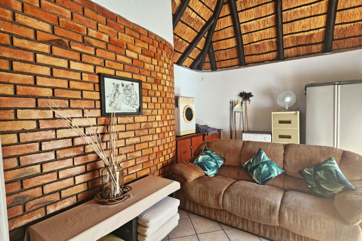 A living area featuring a distinctive exposed brick wall and a traditional thatched roof with exposed timber rafters.