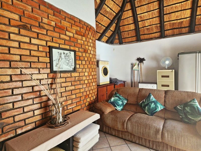 A living area featuring a distinctive exposed brick wall and a traditional thatched roof with exposed timber rafters.