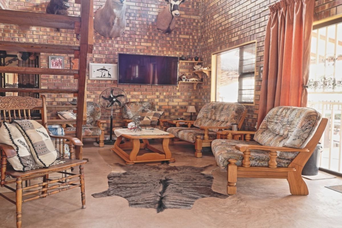 Spacious living room featuring exposed brick walls, concrete flooring, and a wooden staircase, with direct access to an outdoor area via sliding glass doors.