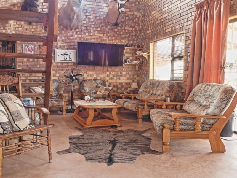 Spacious living room featuring exposed brick walls, concrete flooring, and a wooden staircase, with direct access to an outdoor area via sliding glass doors.