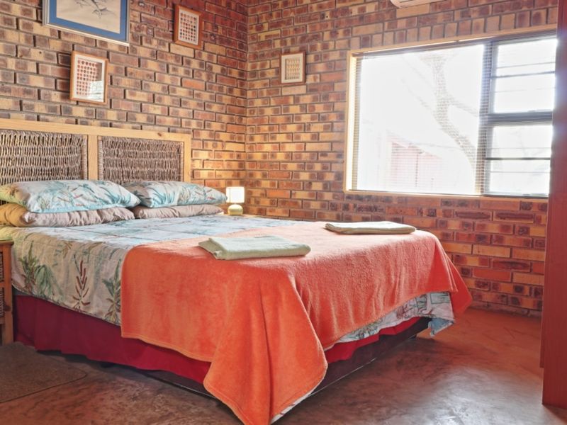 A bedroom featuring exposed brick walls, a window, and an integrated air conditioning unit, offering a rustic aesthetic.