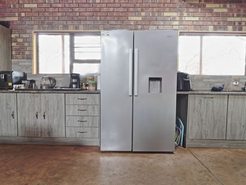 A rustic kitchen featuring exposed brick walls, modern laminate cabinetry, granite countertops, and durable concrete flooring with integrated sink and workspace.
