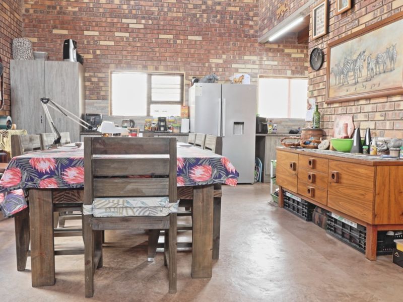 Spacious open-plan living and kitchen area featuring rustic exposed brick walls, concrete flooring, and functional built-in cabinetry.