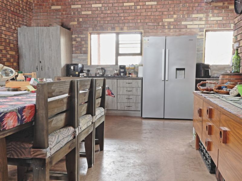 A rustic kitchen featuring exposed brick walls, concrete flooring, and built-in cabinetry, offering a functional space with a distinct industrial aesthetic.