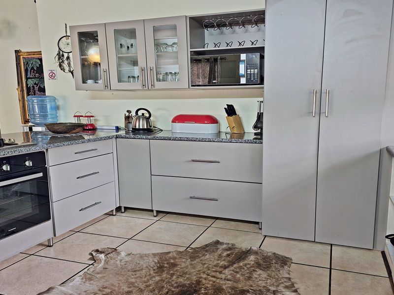 A functional kitchen featuring light grey cabinetry, granite countertops, a built-in oven with gas hob, and tiled flooring.