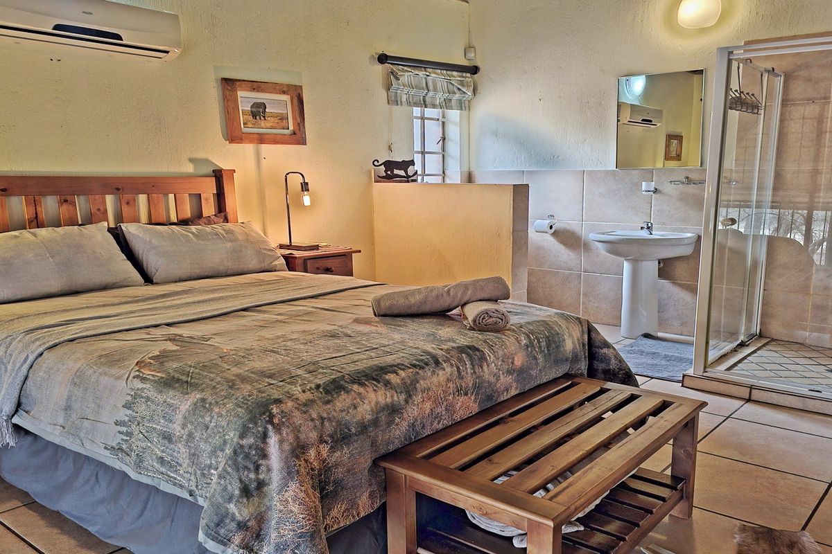 A bedroom featuring an open-plan layout with an integrated en-suite bathroom, including a pedestal basin and a glass-enclosed shower.