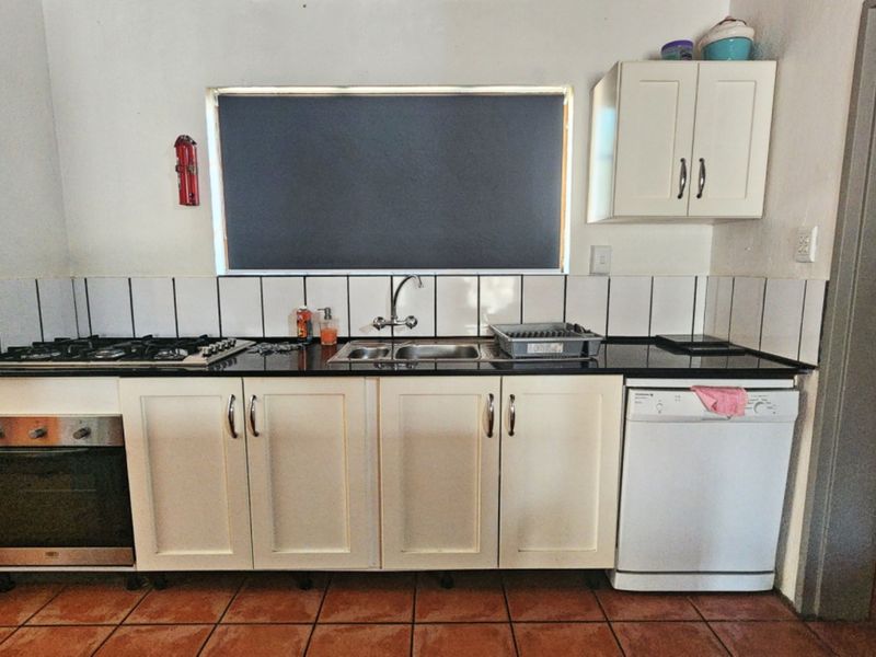 A functional kitchen featuring built-in cabinetry, a gas hob, an integrated oven, a double sink, and tiled flooring with a tiled backsplash.
