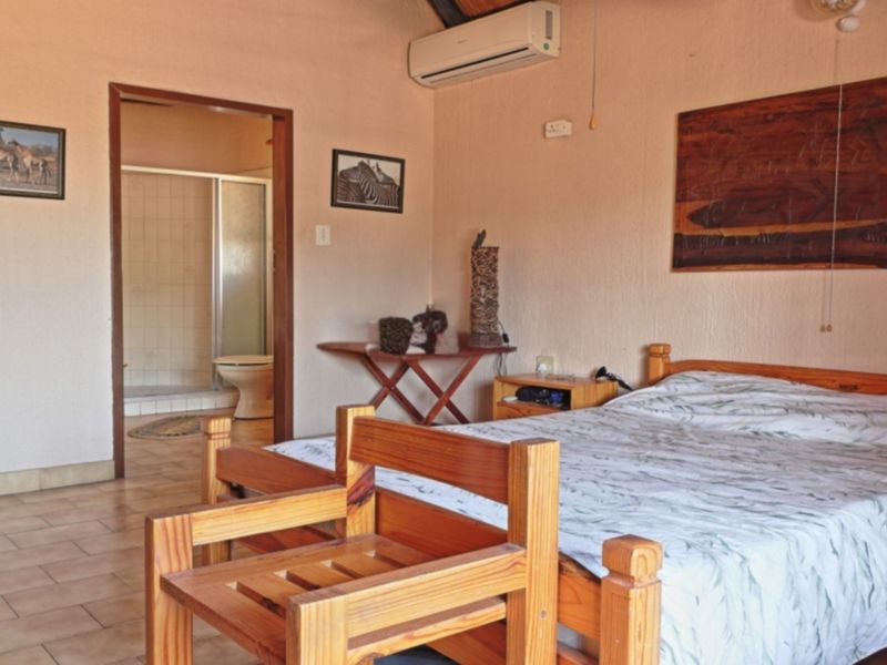 A bedroom featuring tiled flooring, a split-system air conditioner, and direct access to an en-suite bathroom with a shower.