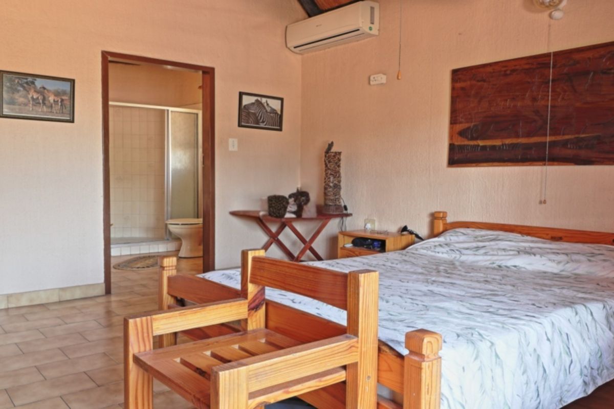 A bedroom featuring tiled flooring, a split-system air conditioner, and direct access to an en-suite bathroom with a shower.