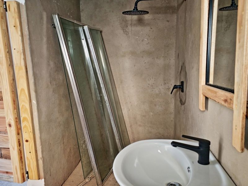 A bathroom in progress featuring a modern basin, matte black fixtures, and unfinished concrete-style walls, awaiting final installation and completion.