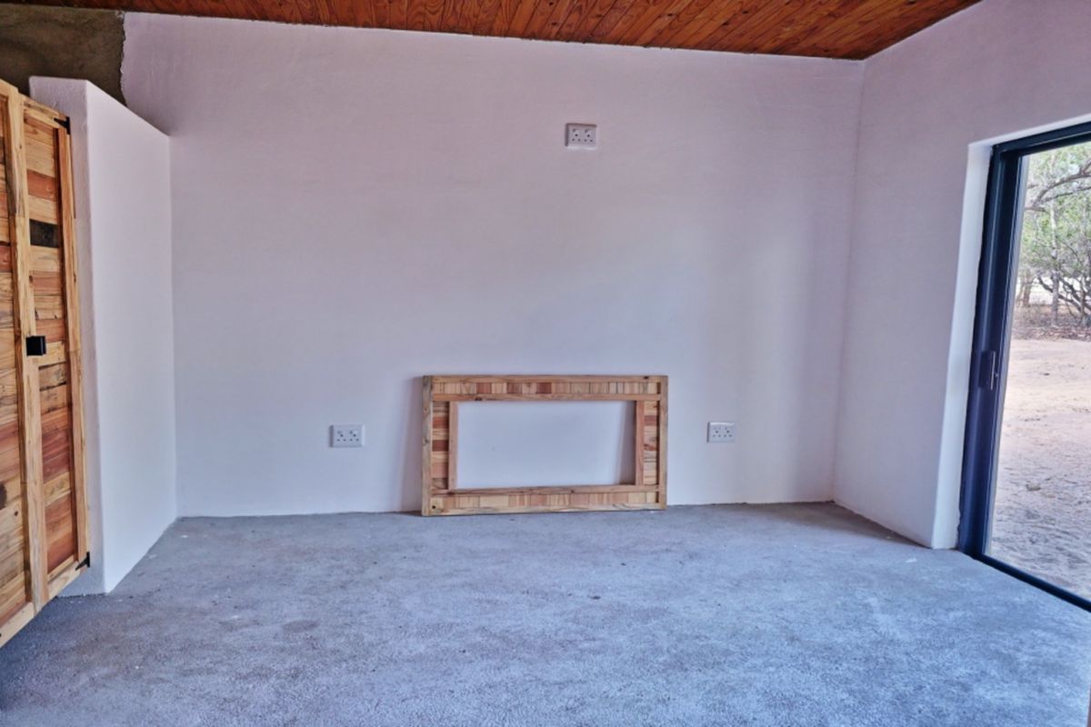 An empty bedroom featuring a timber ceiling, built-in wooden cupboard, and a sliding glass door leading to the exterior.
