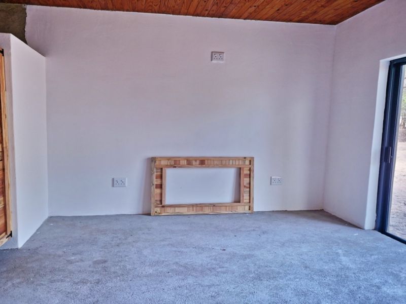 An empty bedroom featuring a timber ceiling, built-in wooden cupboard, and a sliding glass door leading to the exterior.