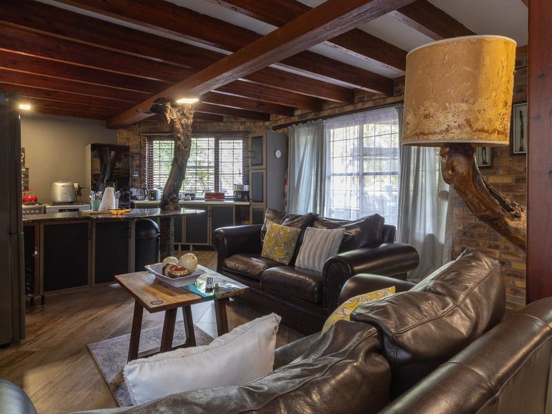 Open-plan living and kitchen area featuring rustic exposed brick walls, timber ceiling beams, and a unique natural wood support pillar.