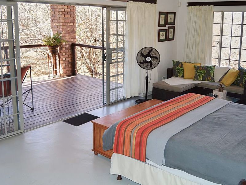 Spacious bedroom featuring large sliding glass doors that open onto a private wooden deck with brick architectural details.