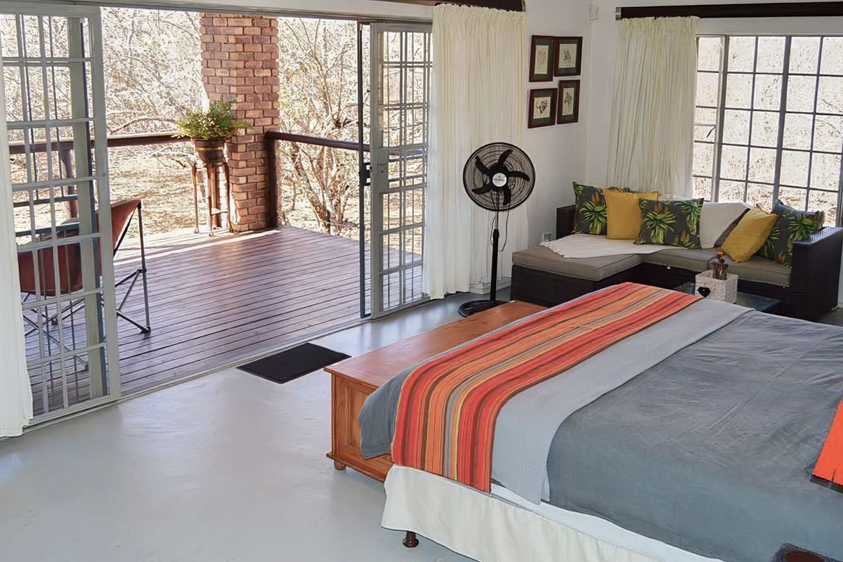 Spacious bedroom featuring large sliding glass doors that open onto a private wooden deck with brick architectural details.