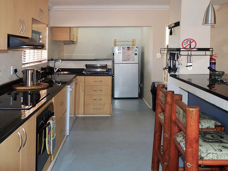 Functional kitchen featuring light wood cabinetry, dark granite countertops, built-in oven, extractor fan, and a convenient breakfast bar for casual dining.