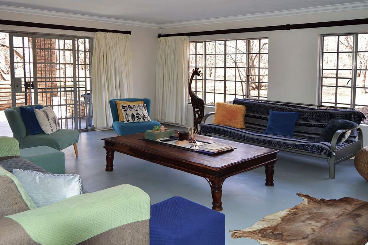 Spacious living room featuring large grid-pattern windows, sliding glass doors leading to the exterior, and painted concrete flooring.