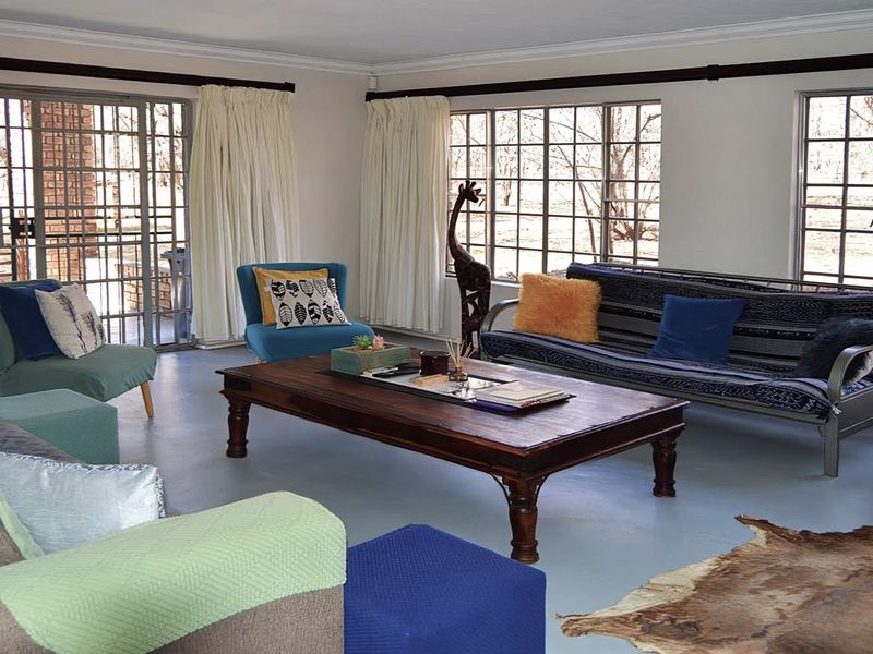 Spacious living room featuring large grid-pattern windows, sliding glass doors leading to the exterior, and painted concrete flooring.