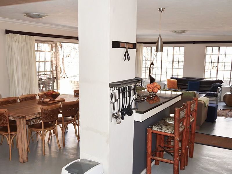 Open plan living and dining area featuring a central kitchen island with built-in hob and direct access to the outdoor space via sliding doors.