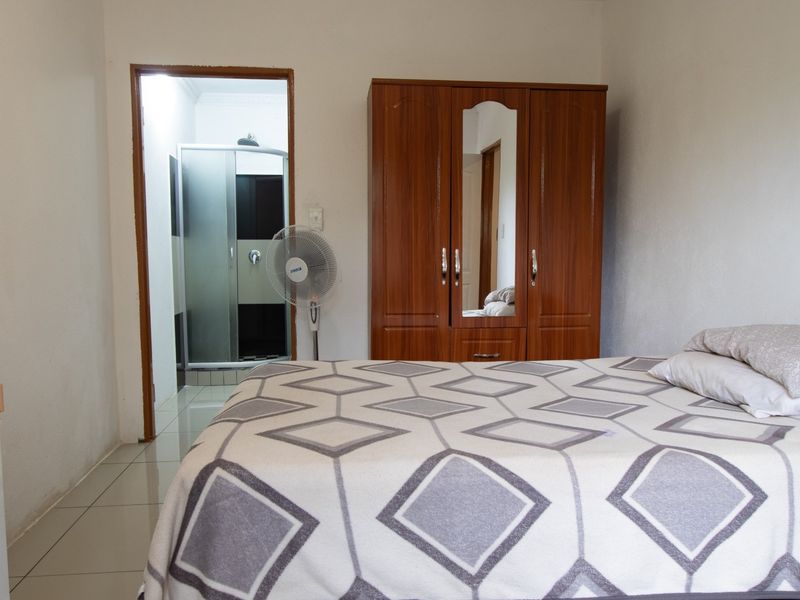 A functional bedroom featuring tiled flooring and direct access to an en-suite bathroom with a shower cubicle.