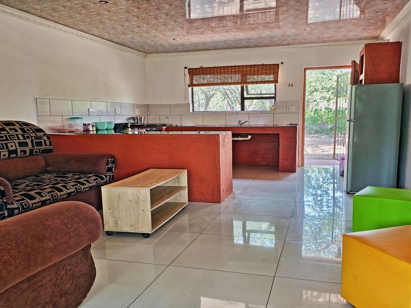 Open-plan living and kitchen area featuring tiled flooring, a built-in kitchen counter with sink, and direct access to the exterior.