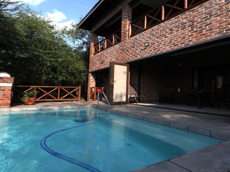 A private swimming pool area featuring a brick-clad exterior, covered patio with bi-fold doors, and a built-in brick braai facility.