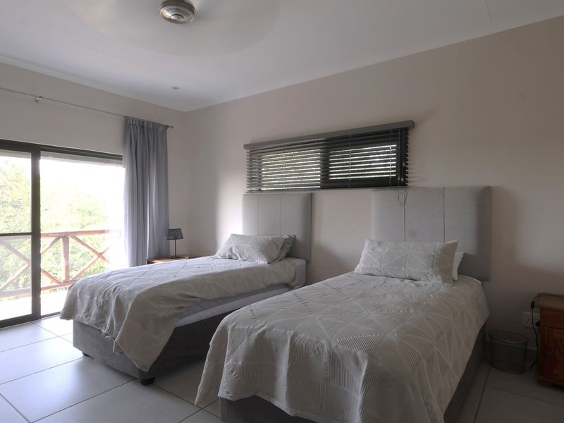 A bright bedroom featuring tiled flooring, a ceiling fan, and a sliding glass door providing access to an outdoor balcony.