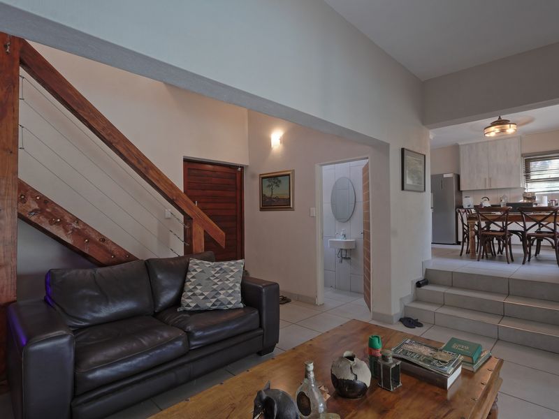 Open plan living area featuring a wooden staircase, tiled floors, and a raised dining space adjacent to the kitchen.