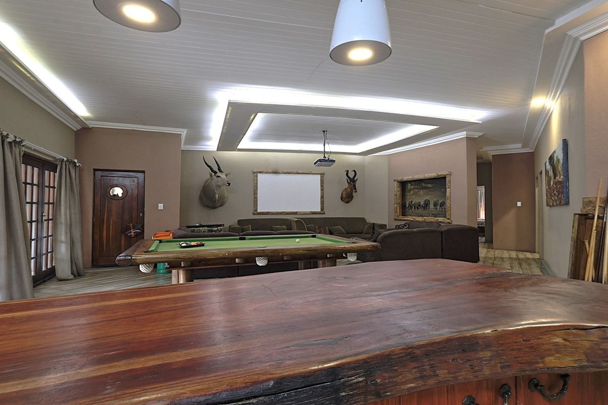 Spacious living area featuring a recessed tray ceiling with cove lighting, a built-in projector, and a large timber bar counter.
