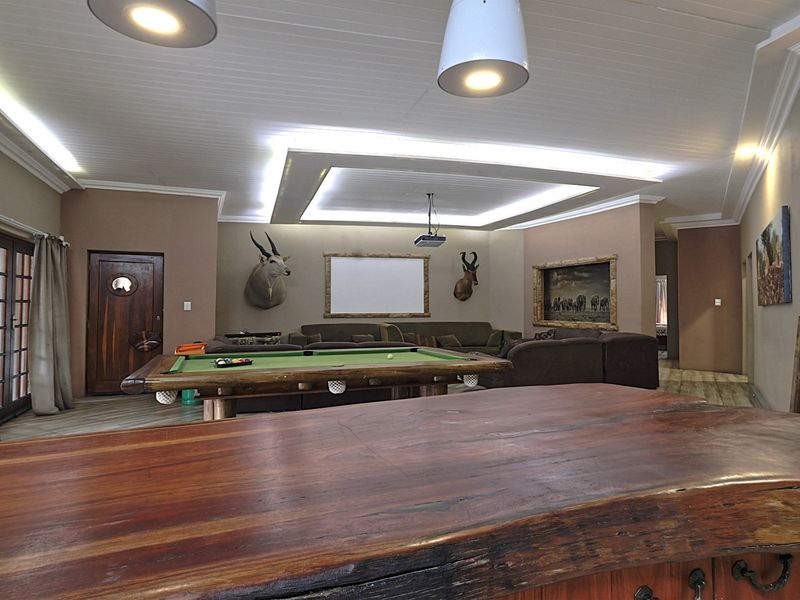 Spacious living area featuring a recessed tray ceiling with cove lighting, a built-in projector, and a large timber bar counter.