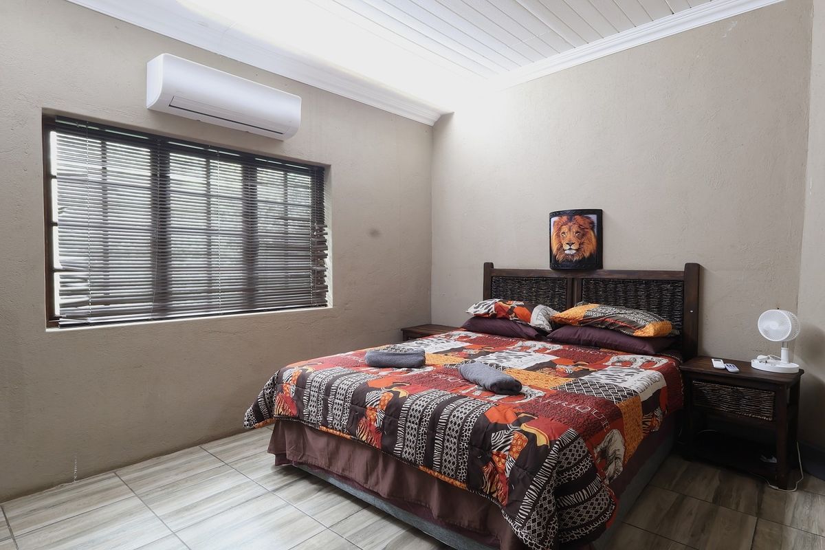 A bedroom featuring tiled flooring, a split-system air conditioner, and venetian blinds, with a tongue and groove ceiling finish.