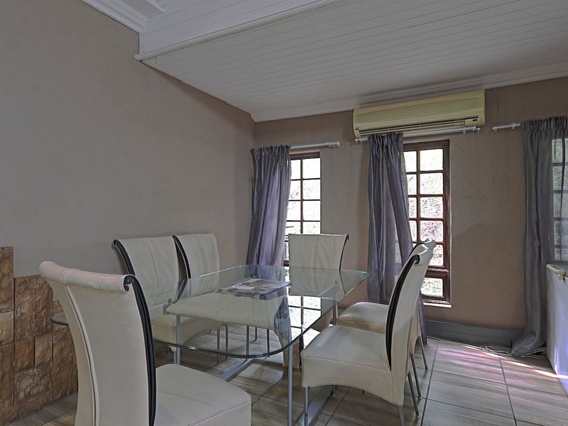 Dining area featuring tiled flooring, stone wall accents, and a split-system air conditioner, offering a functional space with potential for modern updates.