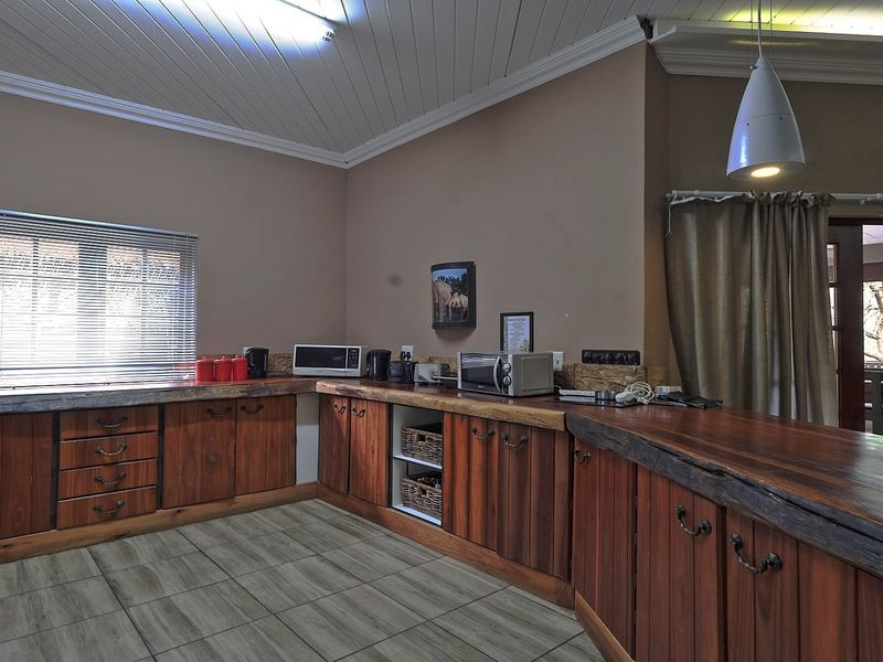 A rustic kitchen featuring custom live edge wooden countertops, dark wood cabinetry, tiled flooring, and a high tongue and groove ceiling.