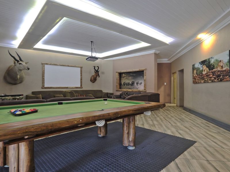 Spacious entertainment room featuring a built-in projection screen, recessed ceiling with ambient LED lighting, and durable tiled flooring.