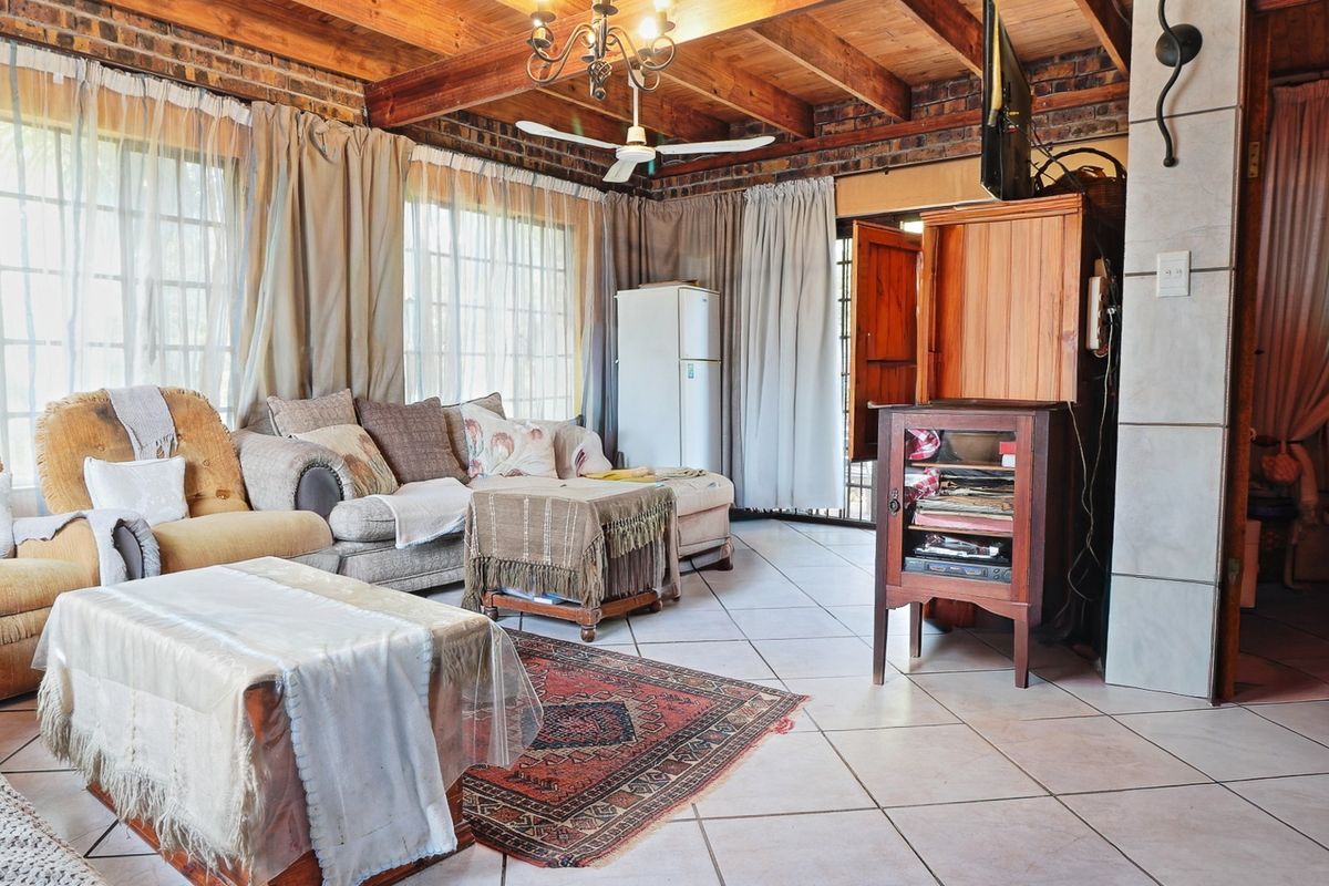 Spacious living area featuring exposed timber ceiling beams, rustic brick walls, and neutral tiled flooring, creating a warm and character-filled atmosphere.