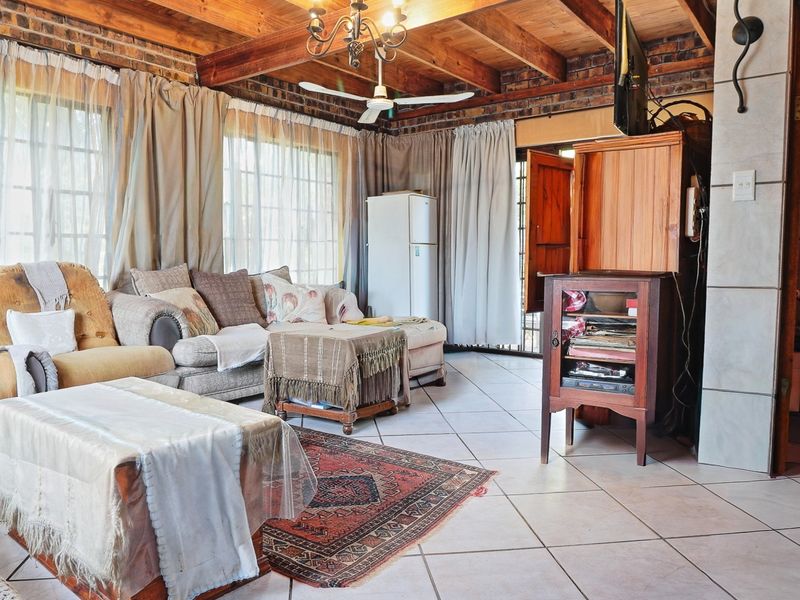 Spacious living area featuring exposed timber ceiling beams, rustic brick walls, and neutral tiled flooring, creating a warm and character-filled atmosphere.