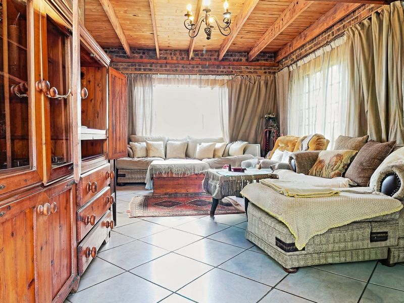 A cozy living room featuring exposed timber beam ceilings, exposed brick accents, and tiled flooring, creating a rustic and warm atmosphere.