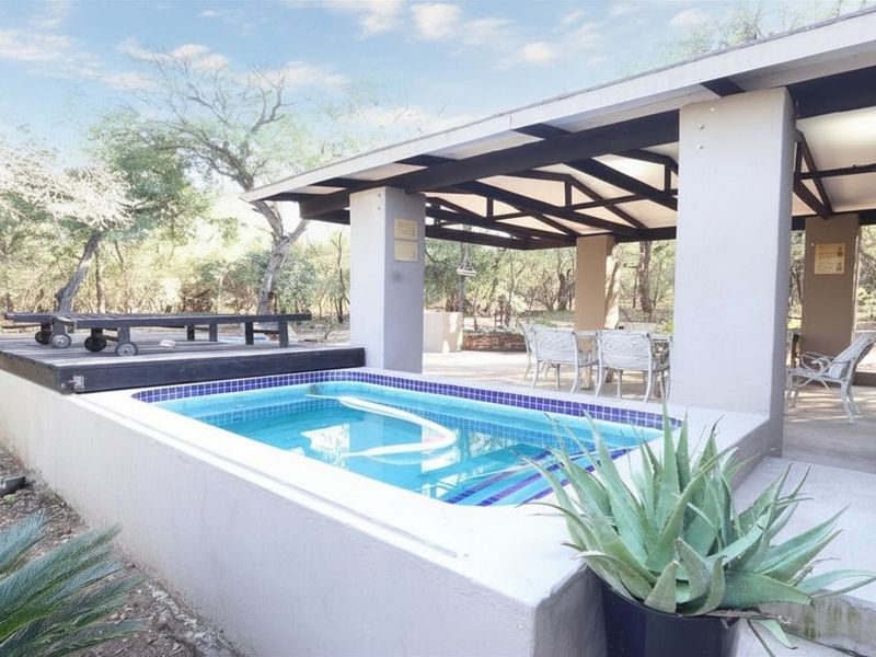 Outdoor entertainment area featuring a swimming pool with tiled coping, adjacent timber decking, and a spacious covered patio structure.