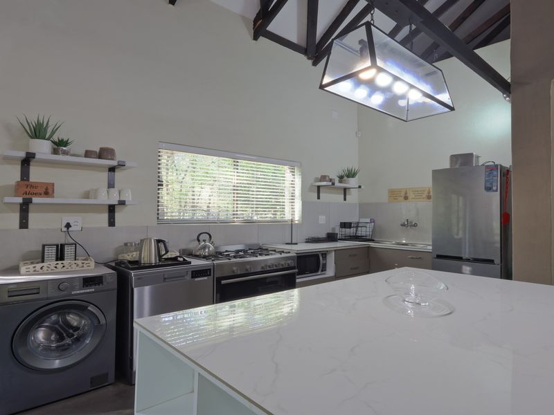 A well-lit kitchen featuring a central island, gas stove, exposed timber rafters, and ample built-in cabinetry with a modern finish.