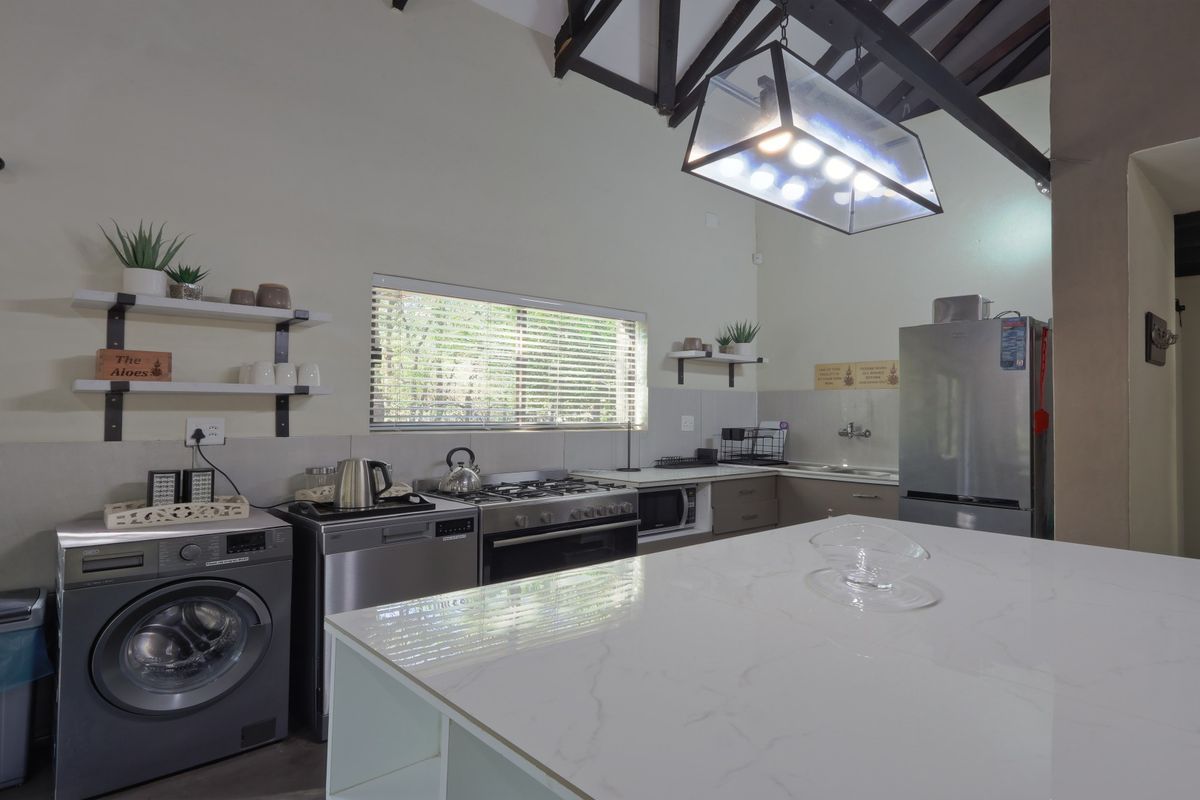 A well-lit kitchen featuring a central island, gas stove, exposed timber rafters, and ample built-in cabinetry with a modern finish.