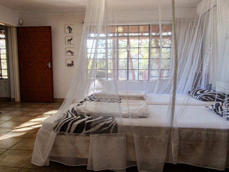 A bedroom featuring tiled flooring, security bars on the windows, and an air conditioning unit.