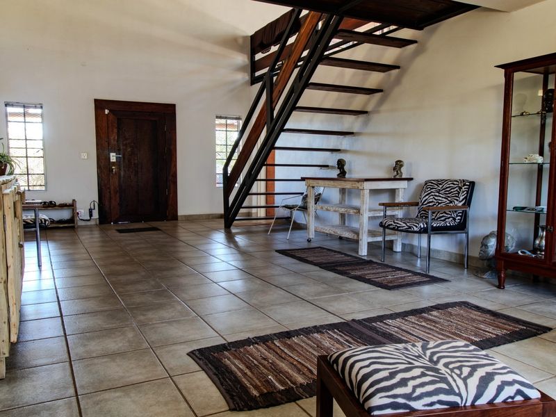 Spacious entrance hall featuring tiled flooring and an open-tread staircase leading to the upper level.